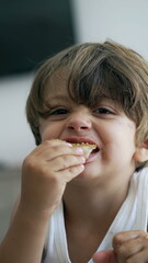 Child snacking peanut butter bread close up face. Portrait of small boy eating food snack in Vertical Video