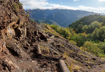 Rock slide damaged a hiking trail along the edge of a volcanic lava rock cliff and a mountain...