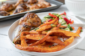 Sweet potato fries with chicken and salad on a plate