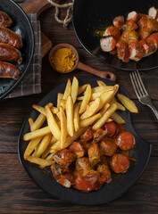 Currywurst with french fries on rustic and wooden table background