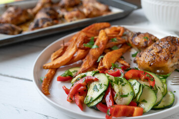 Summer dinner with fresh zucchini, bell peppers salad, grilled chicken and sweet potato fries
