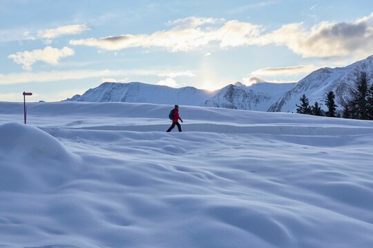 Man hikes snowy trails in Swiss Alps at dawn in winter