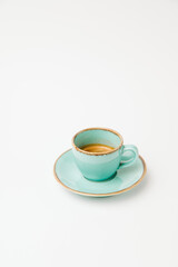 Vertical isolated on white shot of a turquoise cup and saucer of espresso.