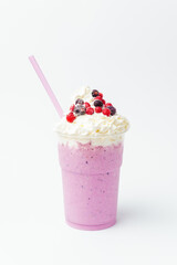 Vertical shot of a tasty berry milkshake with whipped cream and currant on top.