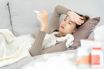 Young Asian woman having high fever while checking body temperature, female sneezing and runny nose with seasonal influenza, allergic, digital thermometer, virus, coronavirus, illness, respiratory.