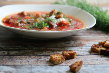 Traditional Ukrainian Borscht with Sour Cream. Red Beetroot Borscht with Dill, Bread, and Garlic on a Wooden Table.