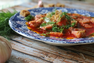 Traditional Ukrainian Borscht with Sour Cream. Red Beetroot Borscht with Dill, Bread, and Garlic on a Wooden Table.
