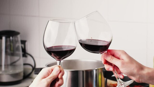 Cheers glasses of red wine, Romantic couple enjoying wine and cooking dinner at home, concept love, relationship and romantic, happy couple celebrating and making cheers with glasses of red wine