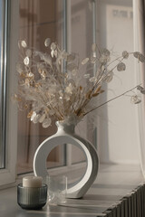 Composition of dried flowers in a vase on the window. Lunaria, lagurus, feather grass