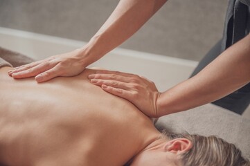 Fototapeta na wymiar Masseur doing back massage to woman in warm atmosphere