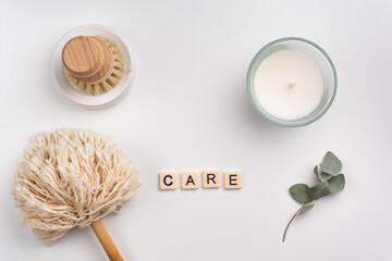 Fototapeta na wymiar sustainable lifestyle concept flat lay with bamboo brush, dusting brush and candle on clean white background. word CARE written with tile letters 