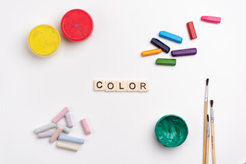 Flat lay of colorful creative supplies. Paints, crayons, chalk and paintbrushes on white...