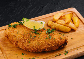 Breaded schnitzel with french fries on a cutting board