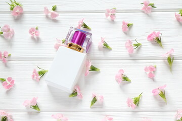 White glass perfume bottle on pink floral background, mockup