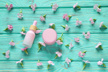Cosmetic bottle with small pink flowers on wooden background, mockup