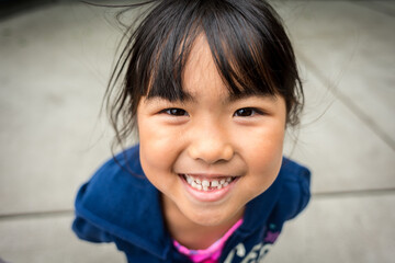 Young asian girl smiling with missing front tooth