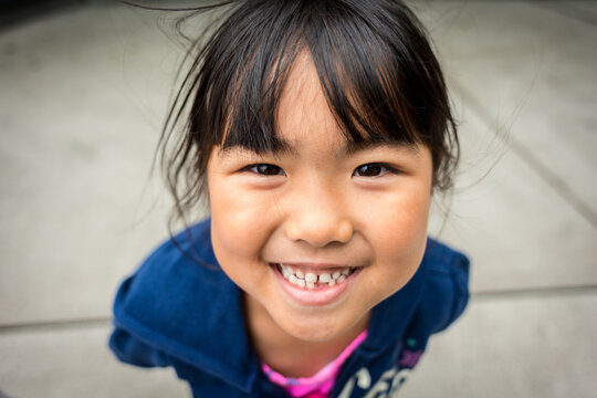 Young asian girl smiling with missing front tooth