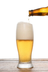 a glass of beer, the bottle spills the drink and the foam overflows the glass