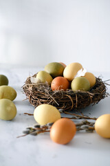 Close-up of a nest of twigs inside with yellow, green and light green easter eggs