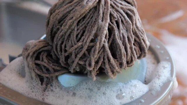 Wringing out a mop in a plastic bucket.