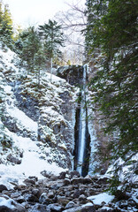 Mountain waterfall with rocks and cliffs covered with snow - 583580200