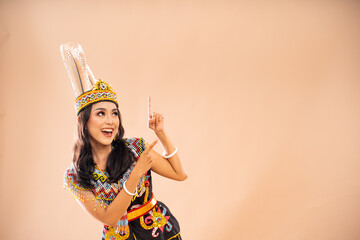 happy asian woman in traditional clothes of dayak tribe looking and pointing up on isolated...