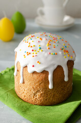 Traditional Ukrainian cake on a green napkin with candles in the shape of eggs on a gray background. The concept of festive Easter baking. Selective focus. Vertical orientation.
