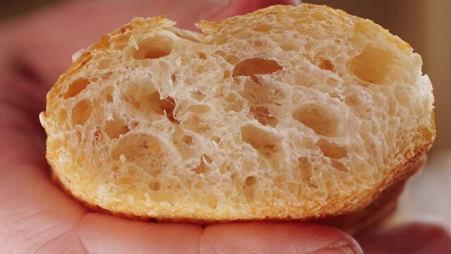 Whole wheat white grain bread close-up macro texture in hands. Man cutting fresh bread with a big knife. Fresh baguette on the kitchen table.