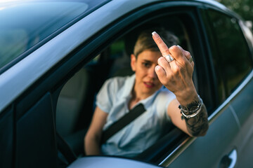 woman senior mature driver show middle finger trough the window of car