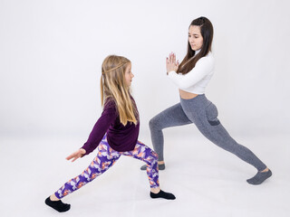 Attractive yoga teacher and her little student doing performing intensive movements while exercising