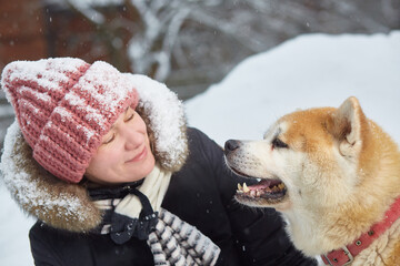 A woman with an akita dog. sports and outdoor recreation on a snowy winter day. Close-up.