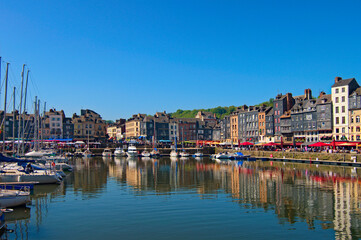 Fototapeta na wymiar Picturesque landscape view of vintage harbour at the ancient Normandy village Honfleur. Boats, yachts are moored along the embankment with open-air cafes. Travel and tourism concept