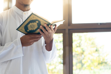Muslim man reading holy Quran. Holy Quran in Hand with arabic text meaning of Al Quran. Islamic...