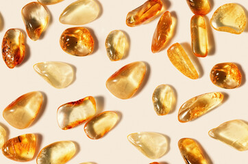 Amber stones on light beige background, minimal monochrome seamless pattern, transparent stone yellow beige color. Natural gemstone mineral. Top view Amber texture. Nature gems at sunlight
