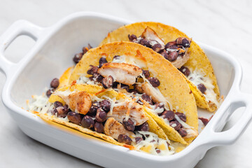 tacos filled with grilled chicken meat, red beans and grated cheese