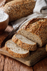 Rustic whole grain bread on a cutting board on a wooden kitchen table