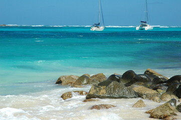 two sail boats floating near coast of Caribbean island