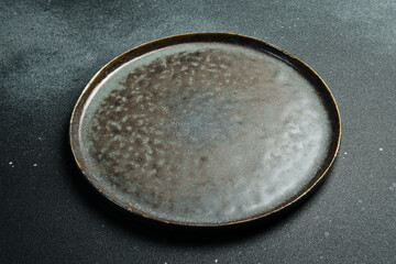 Empty gray plate (ceramic) on a dark gray background. Free space for text. Top view.