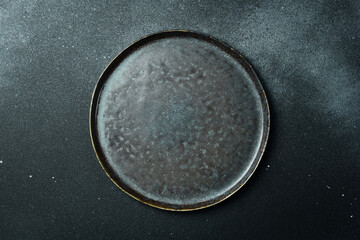 Empty gray plate (ceramic) on a dark gray background. Free space for text. Top view.