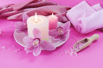 Obraz na płótnie Canvas Fresh pink orchid flowers, burning candles, sea salt, on a bright pink background, spa concept, relaxation atmosphere, body care 