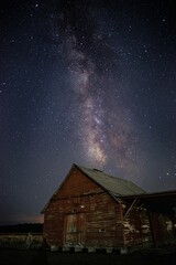 Mesmerizing vertical view of the magical starry night over an old wooden barn