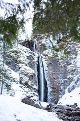 Mountain waterfall with rocks and cliffs covered with snow - 583598458