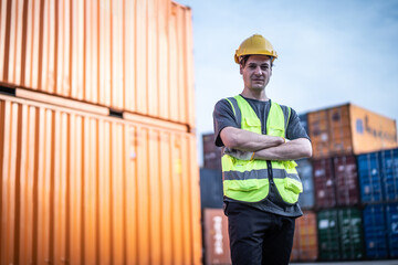 Caucasian warehouse worker in uniform with hard hat standing in container port terminal. Area logistics import export and shipping.