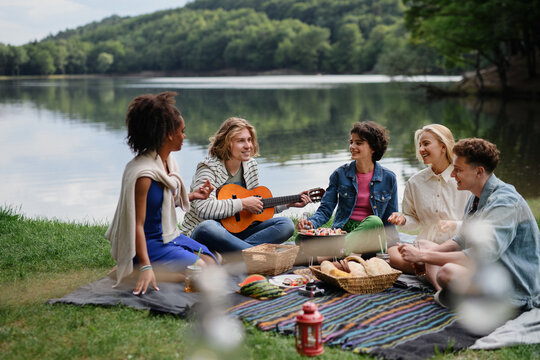 Group of multiracial young friends camping near lake and and having barbecue together.