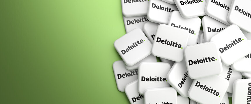 Logos of the Big Four accounting organization Deloitte on a heap on a table. Web banner format with copy space
