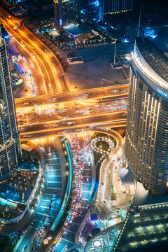Dubai, UAE, United Arab Emirates - May 25, 2021: Aerial View Of Urban Background Of Illuminated Cityscape With Towers In Dubai. Street Night Traffic In Dudai Skyline. Moving Through Modern City Street