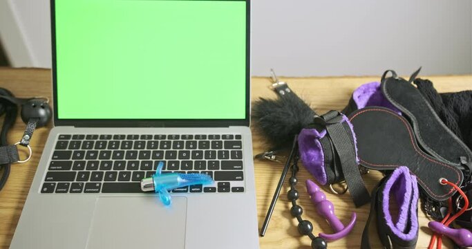 Small vibrator with rings around the edges spins in circle on laptop with green screen. Top view, close-up. Concept of online app, store, sex shop.