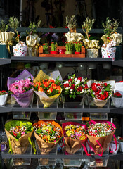 A flower shop window. Shelves with different bouquets of flowers.