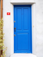 Old blue wooden door in white wall.