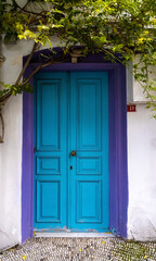 Fototapeta na wymiar Old blue wooden door with violet frame in white wall. European architectural exterior poster.